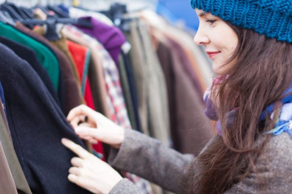 Attractive woman choosing clothes at flea market.