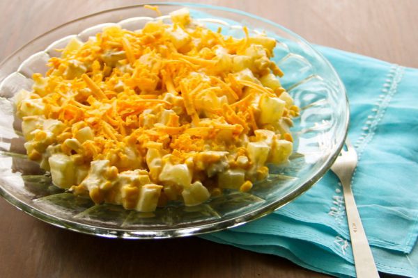 Festive salad with chicken breast, sweet corn, cheese and pineapple on wooden table