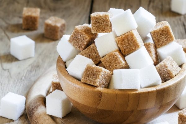 Cubes of white and brown sugar, wooden bowl, selective focus
