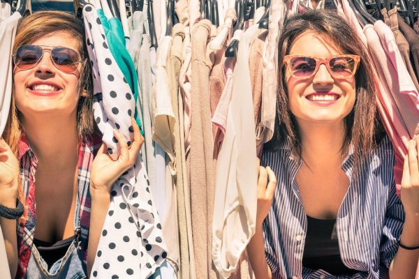 Young beautiful women at the weekly cloth market - Best friends sharing free time having fun and shopping in the old town in a sunny day - Girlfriends enjoying everyday life moments