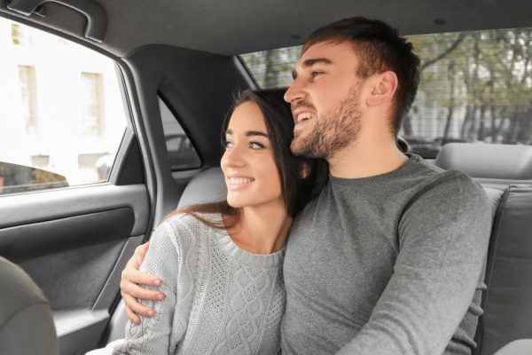 Happy young couple on back seat of taxi car