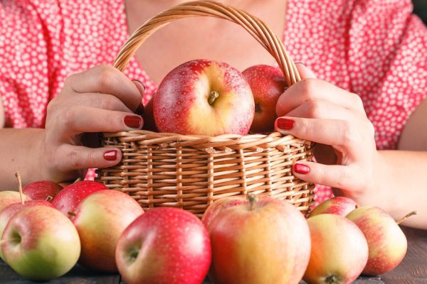woman  holding a basket of apples
