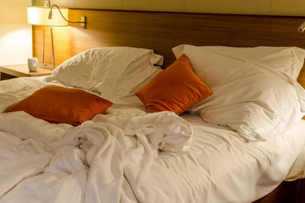 Unmade bed with white linens