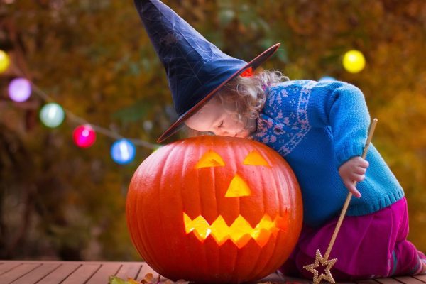 Little girl and boy carving pumpkin at Halloween. Dressed up children trick or treating. Kids trick or treat. Child in witch costume playing in autumn park. Toddler kid with jack-o-lantern.