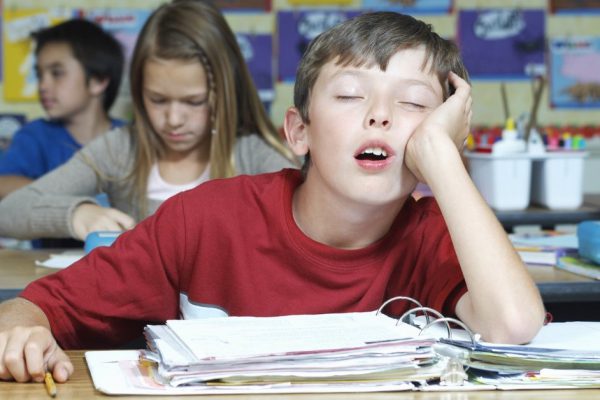 Three pupils in classroom, one of them sleeping