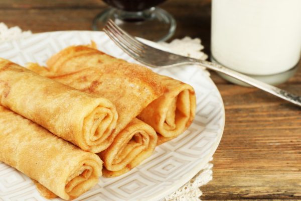 Plate of delicious pancakes with berry jam and glass of milk on wooden background