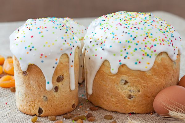 Traditional russian easter cake also called kulich with sugar icind, dried apricots and raisins on vintage textile  background