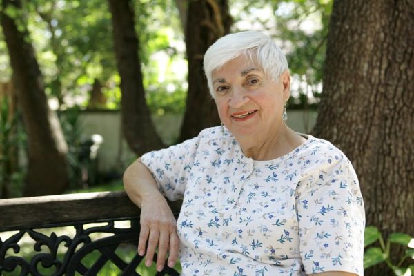 A sweet senior lady relaxing on a park bench.   Room for text.