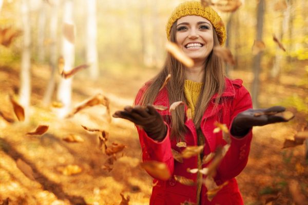 Happy woman throwing leaves