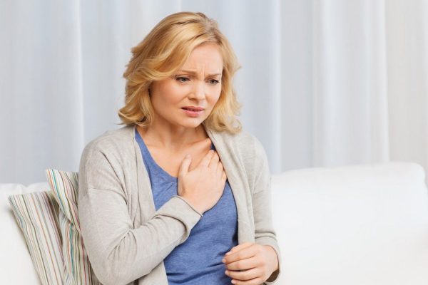 people, healthcare, heart disease and problem concept - unhappy woman suffering from heartache at home