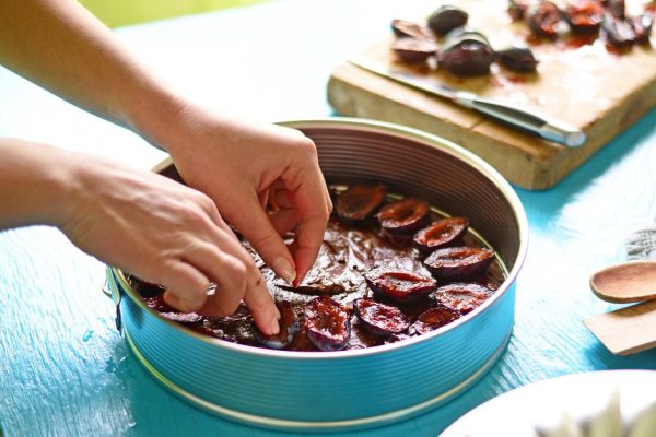 Woman preparing chocolate cake with plums