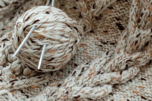 Detail of woven handicraft knit woolen design texture and knitting needle. Fabric beige background