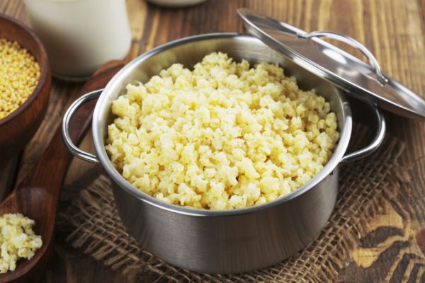 Millet porridge in a metal pan on the wooden table