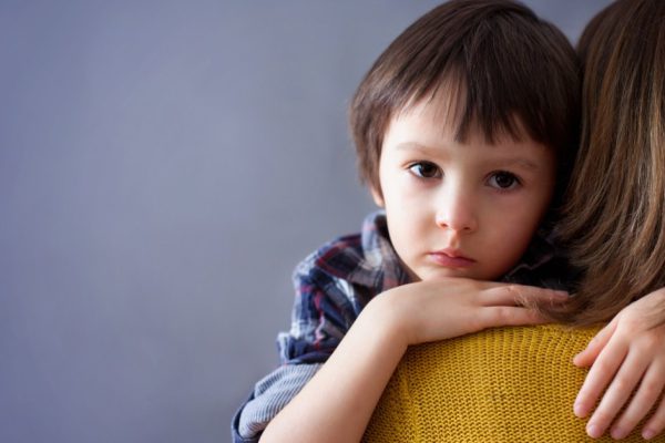 Sad little child, boy, hugging his mother at home, isolated image, copy space. Family concept