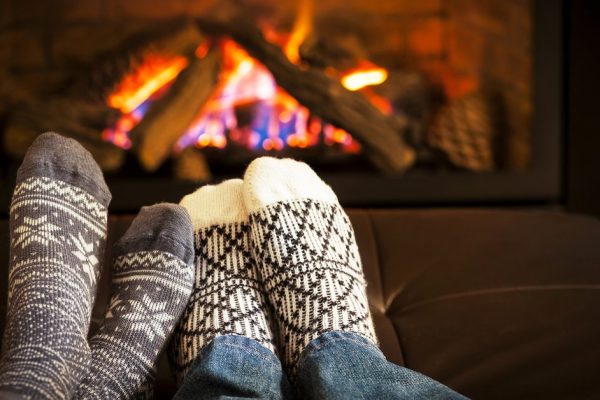 Feet in wool socks warming by cozy fire