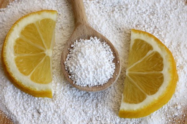 citric acid in wooden spoon with lemon, close-up