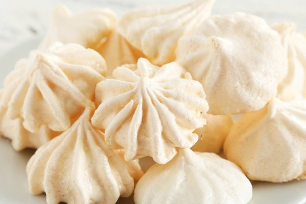 French meringue cookies on plate on white wooden background