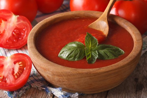 Fresh red tomato ketchup and basil in a wooden bowl closeup. horizontal