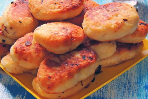 homemade sauerkraut pies on a wooden table, a basket of pies and lemon tea