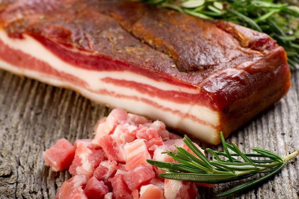 slice bacon with rosemary on wood background