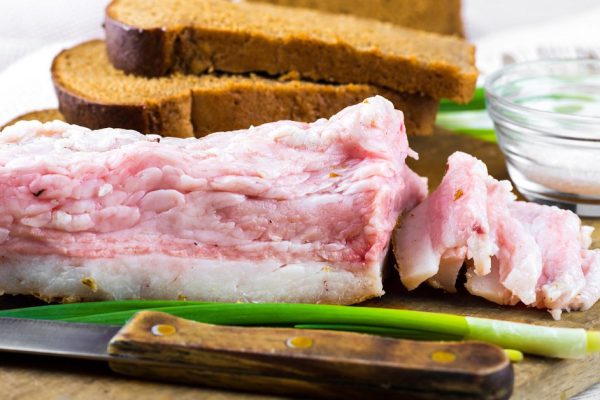 Bacon with onion and garlic on a wooden board