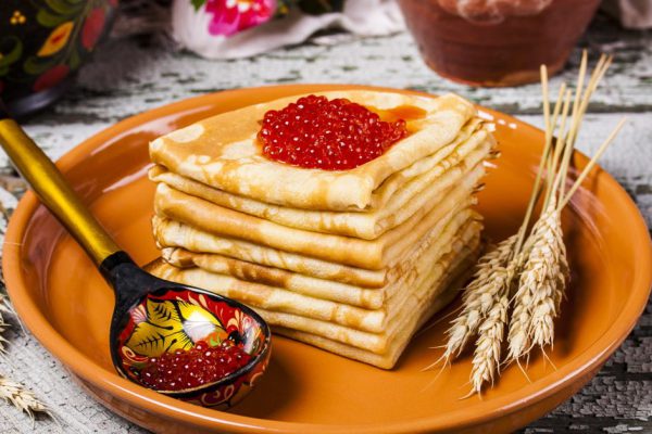 Pancakes with salmon caviar traditional Russian meal on wooden background
