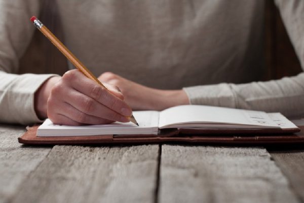 hand writes with a pen in a notebook