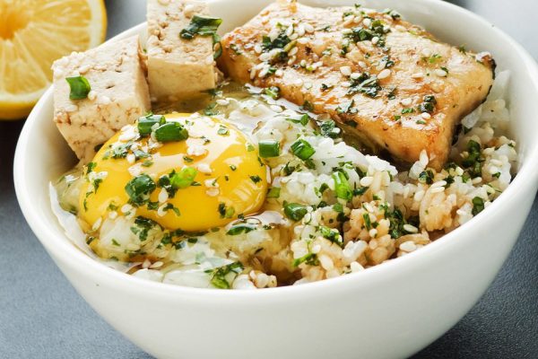 Bowl with jasmine rice, raw egg, sturgeon and vegetables. Shallow dof.