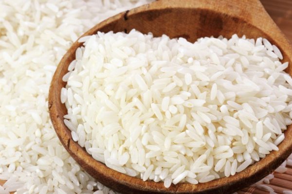 Uncooked white rice in a wooden spoon. Shallow DOF.