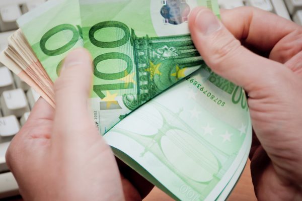 Mani di uomo contano denaro con sfondo della tastiera di computer