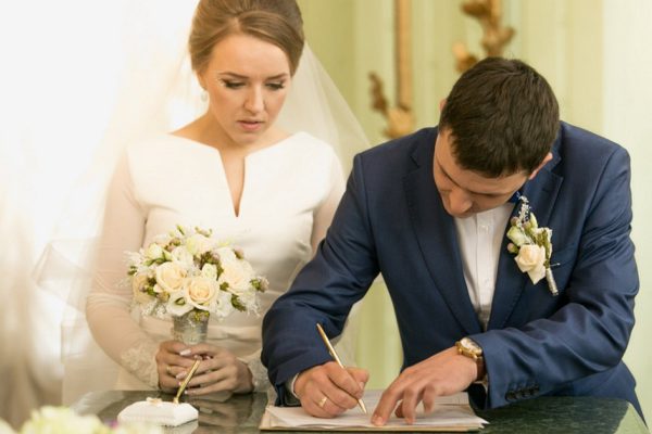 Closeup portrait of young groom signing wedding contract at registry office