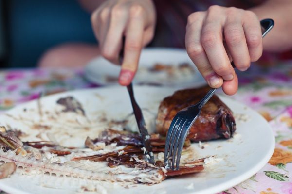 Closeup on a woman's hands as she is cutting a fish in a restaurant