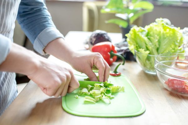 Salad. Male hands cutting green leaves of lettuce on a cutting board for vegetable salad.