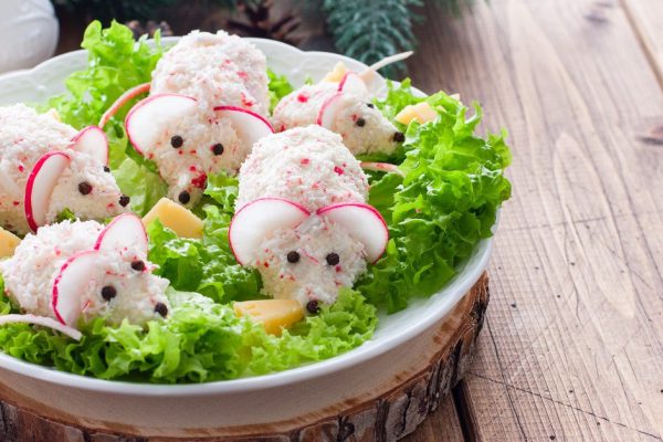 Festive Christmas crab salad in the form of mice on a platter with pieces of cheese, horizontal, copy space