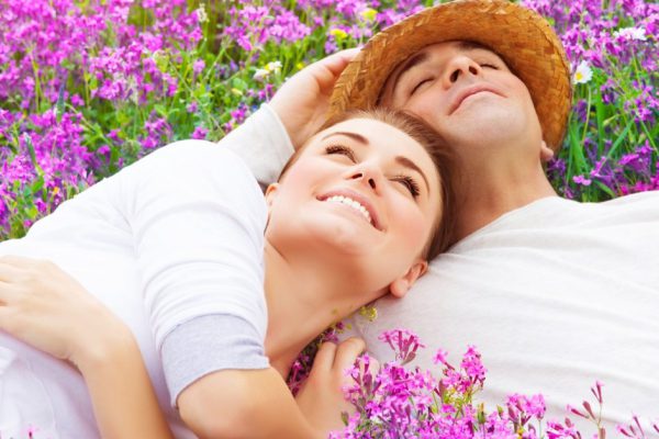 Handsome man with attractive woman lying down on fresh lavender field, enjoying each other, romantic relationship, love concept