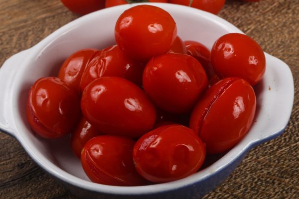 Pickled cherry tomatoes heap on the wooden background