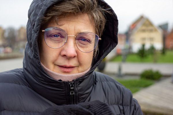 Mature plump woman in a black jacket with a hood resting in a city Park, close-up
