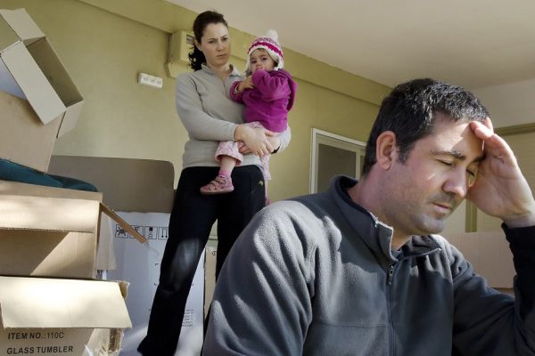 Young parents and their daughter stand beside cardboard boxes outside their home. Concept photo illustrating divorce, homelessness, eviction, unemployment, financial, marriage or family issues.