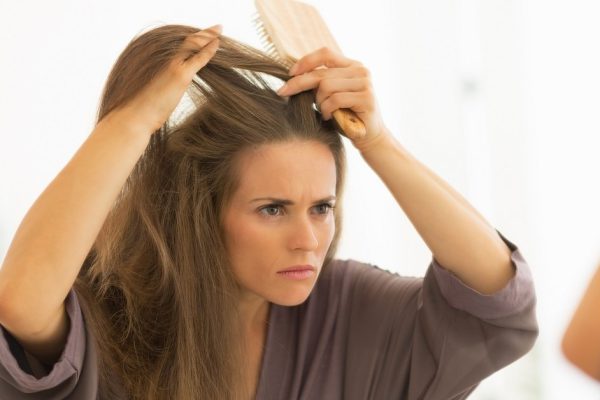 Concerned young woman combing hair in bathroom