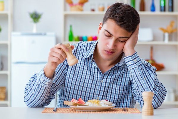 Young husband eating tasteless food at home for lunch