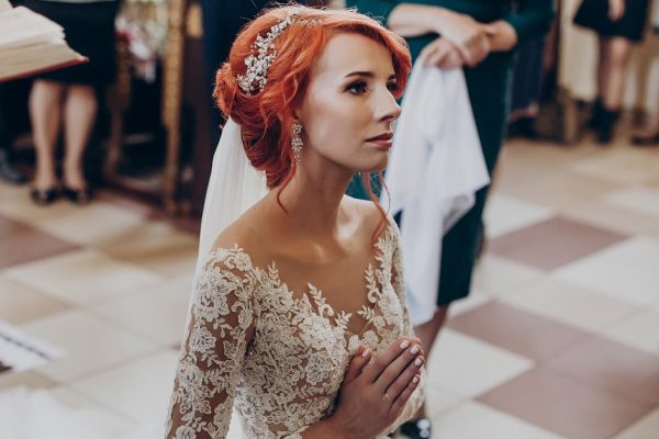 stylish bride praying during matrimony wedding ceremony in church. emotional moment, space for text. religion unity concept . spiritual couple