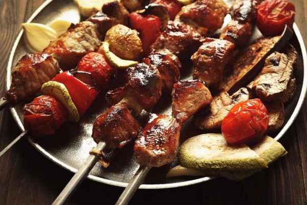 Fresh tasty barbecue with vegetables on tray on wooden background
