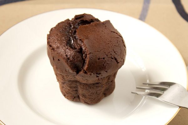 Small french chocolate cake made in muffin mold on the white plate with fork