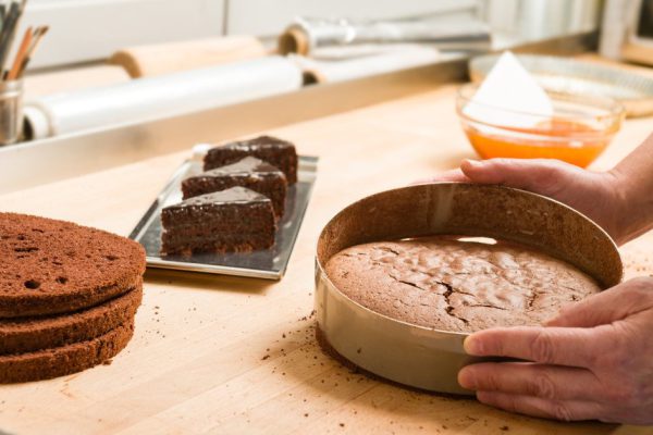 Cook taking out layer cake from cake form