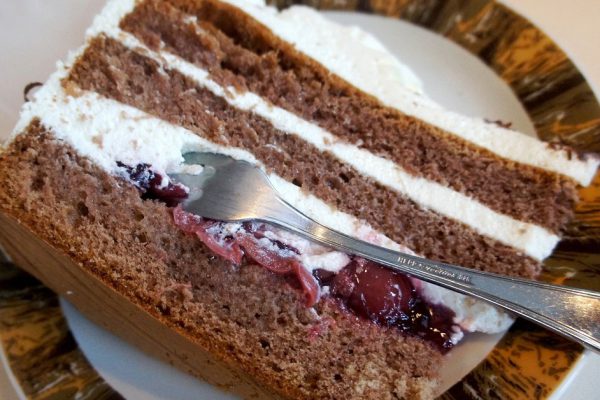 Ein Stück Schwarzwälder Kirschtorte auf einem Teller mit einer Kuchengabel; dunkler Teig im Wechsel mit Sahne und Kirschfüllung; deutsche Spezialität aus dem Schwarzwald
A piece of Black Forest cake on a plate with a pastry fork; darker dough, alternating with cream and cherry filling; German Specialty from the Black Forest