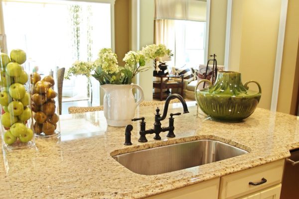A granite topped island counter in a modern kitchen with dark hardware