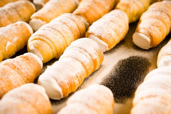 Puff pastries filled with whipped cream in powder sugar coating