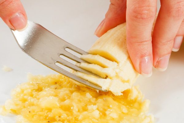 A cook muching a banana for cookies -  or it can be a mother making  banana puree for baby