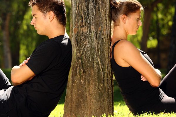 A picture of a young couple sitting in the park and being in a conflict