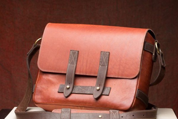 Old vintage leather bag with leather strap on wooden table